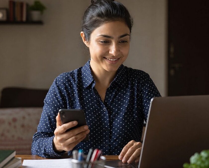 Young Indian woman using a laptop and phone to make a resume with AI se resume kaise banaye